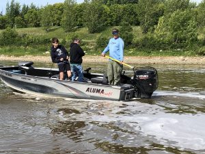 2 anglers fighting catfish with fishing guide ready to net fish 