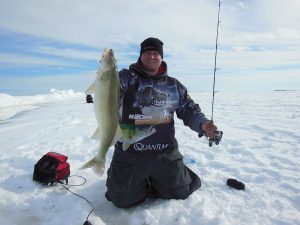 Man on frozen lake ice fishing